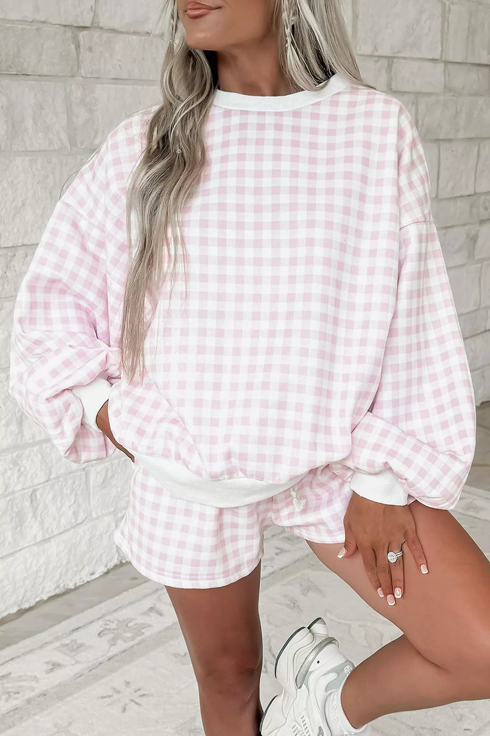 Blush pink gingham sweatshirt worn oversized with a hand in the pocket and sneakers