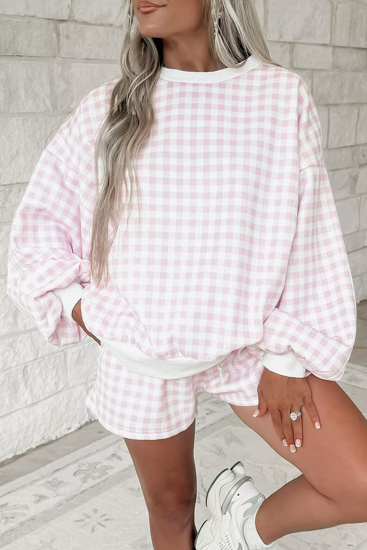 Blush pink gingham sweatshirt worn oversized with a hand in the pocket and sneakers