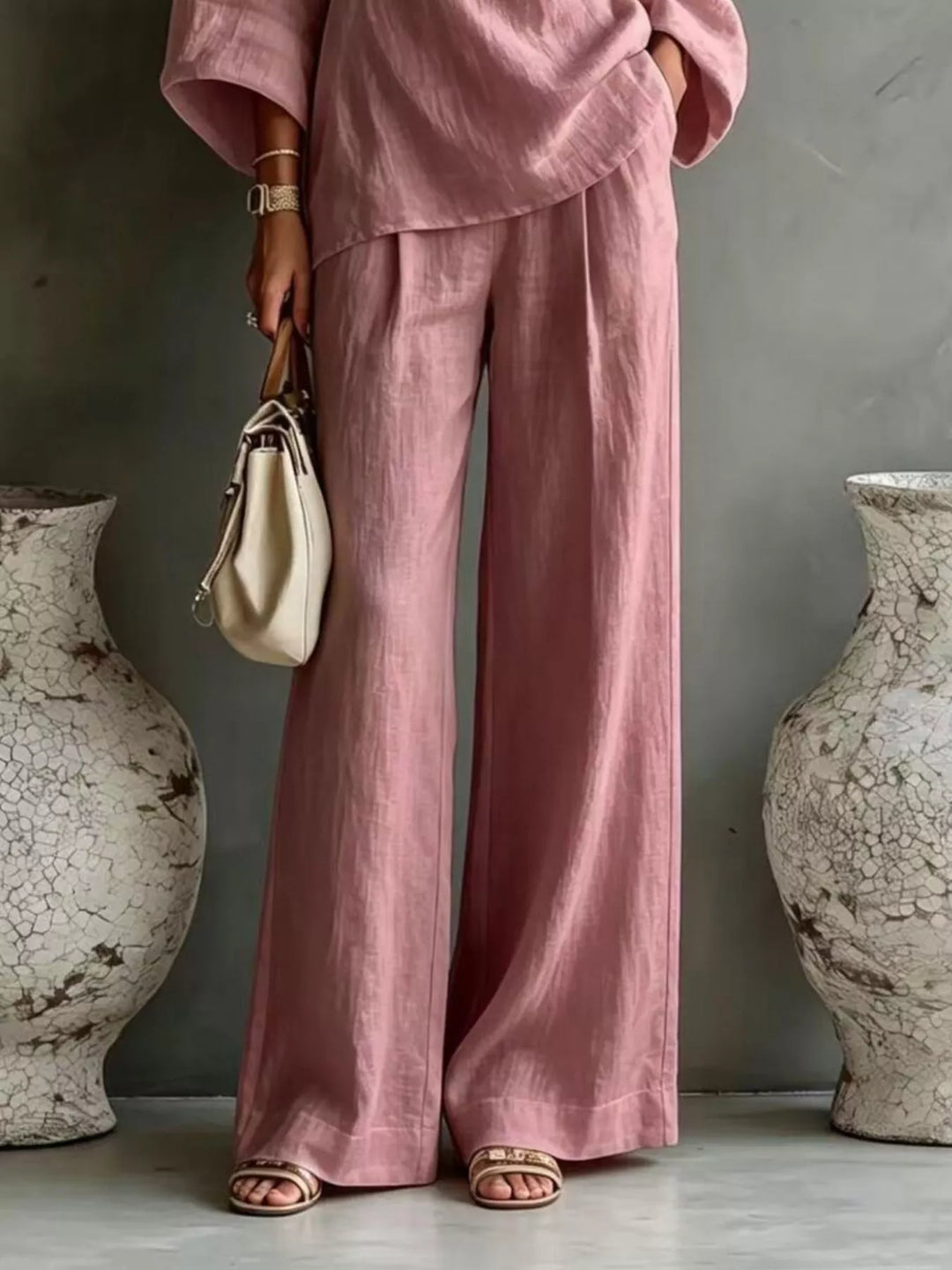 Dusty pink wide leg pants and top set worn with a cream handbag