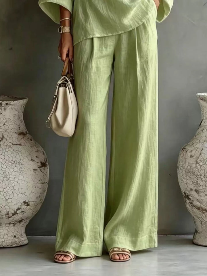 Pistachio green wide leg pants and top set worn with a cream handbag
