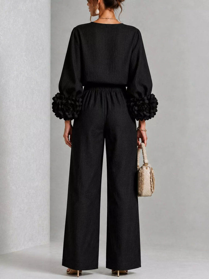 Black matching set with ruffled cuffs, standing pose holding a handbag