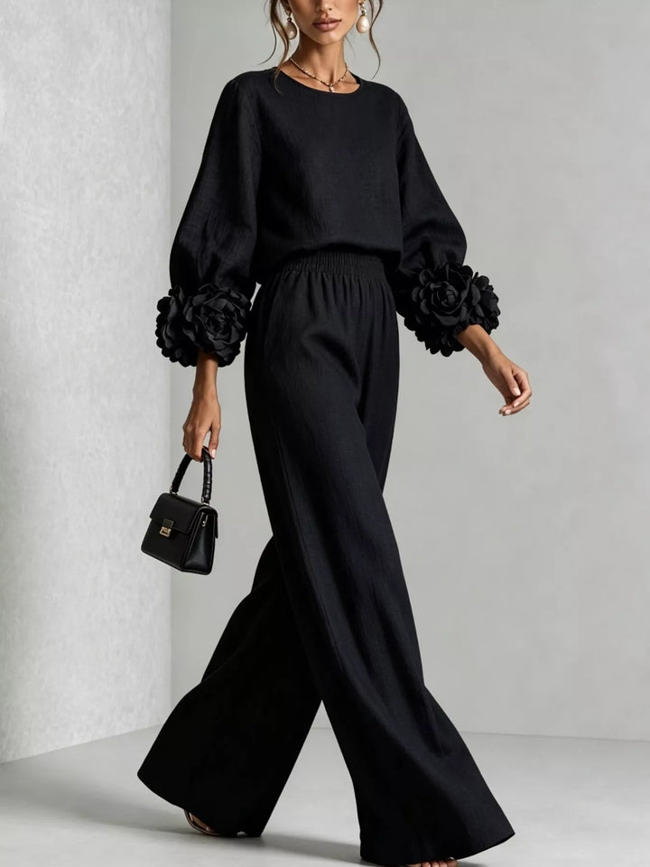 Black matching set, model walking in wide leg pants with a small handbag