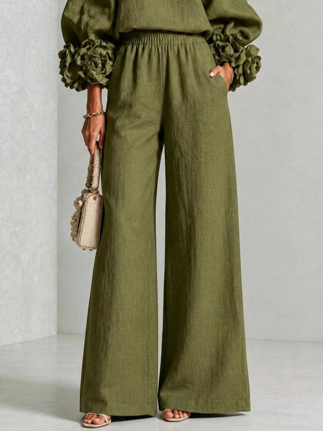 Detail of the moss wide leg pants with pockets and a small handbag
