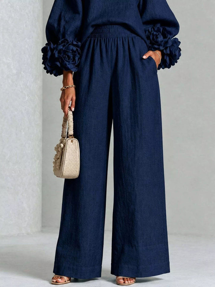 Detail of the navy wide leg pants and ruffled cuffs holding a handbag