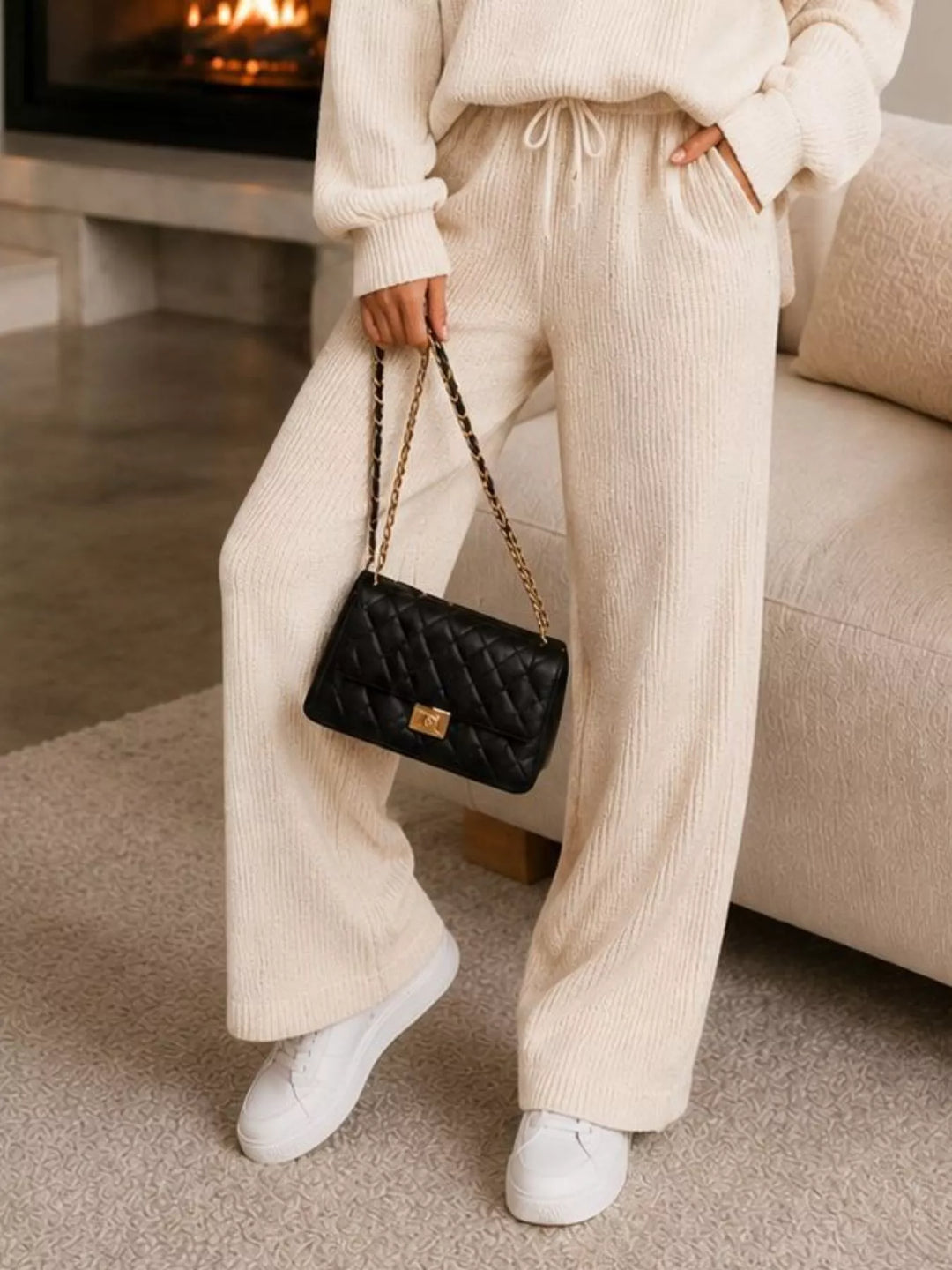 Detail of the cream ribbed wide leg pants with white sneakers and a bag