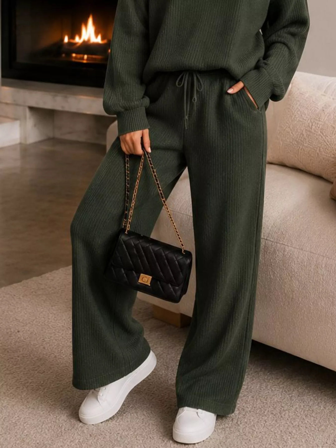 Detail of the dark green wide leg pants with white sneakers and a chain bag