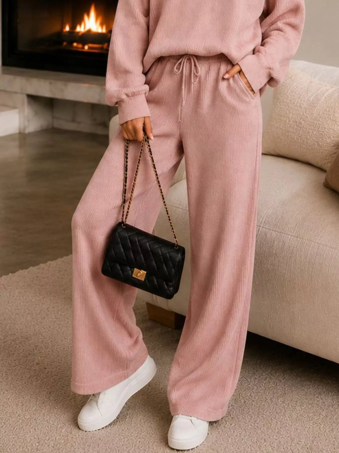 Detail of the dusty pink ribbed wide leg pants with a chain strap bag