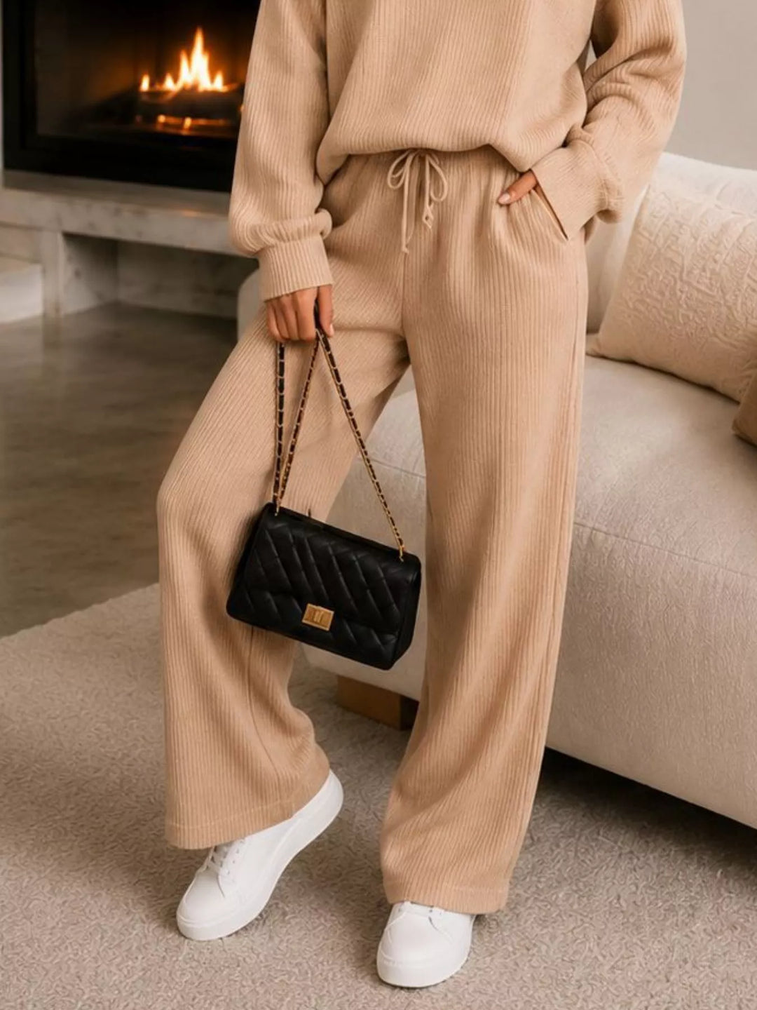 Detail of the tan wide leg pants with a quilted bag and white sneakers
