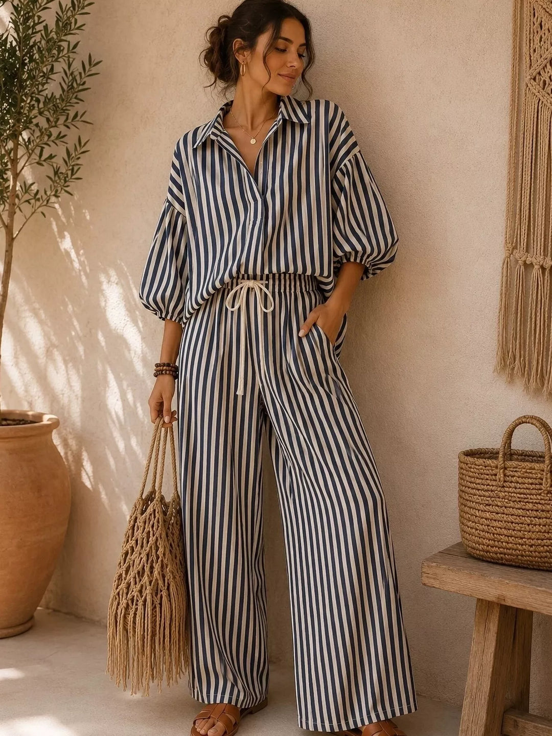 Black striped collared shirt and wide leg pants set, standing with a woven bag