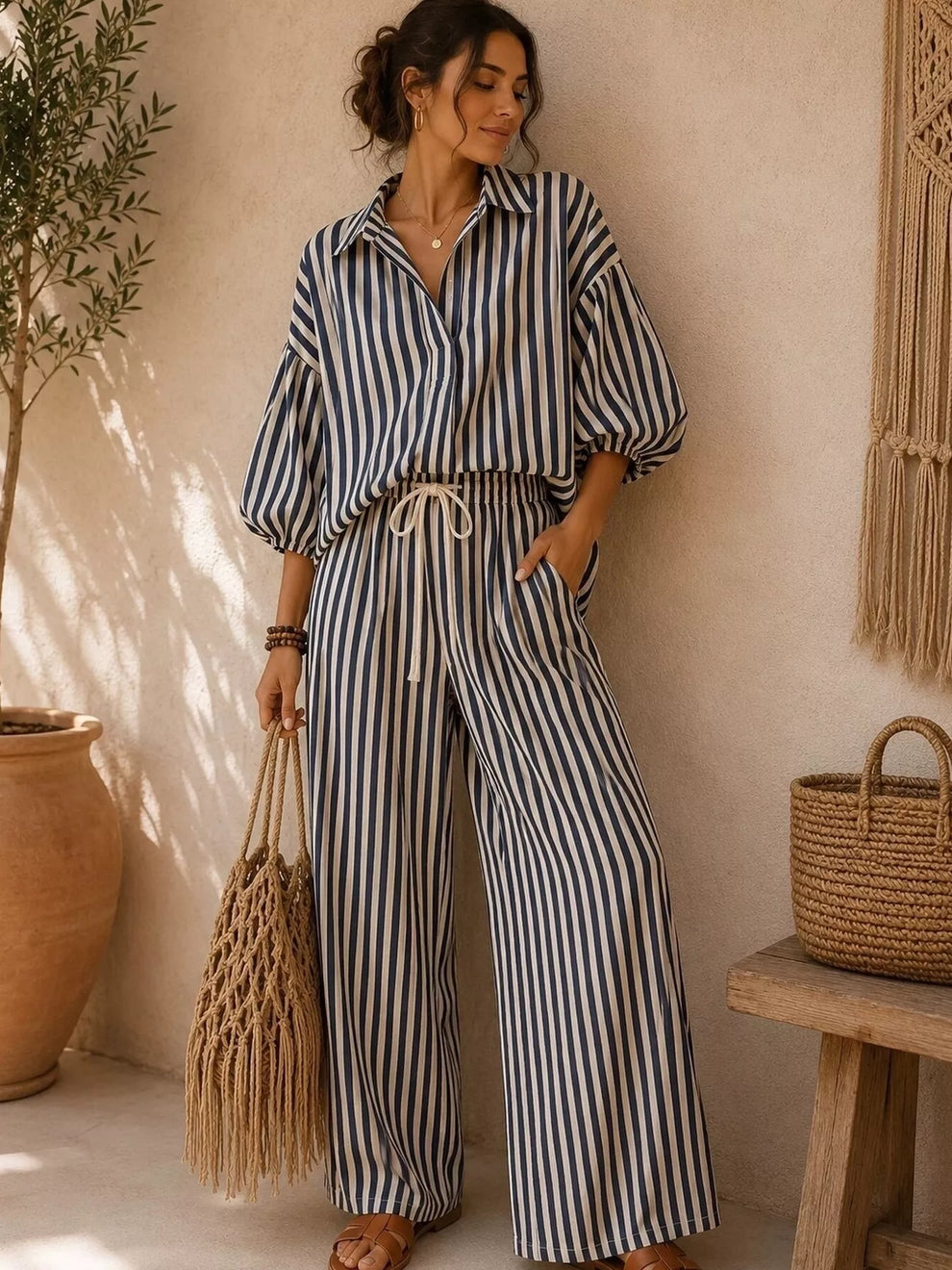 Black striped collared shirt and wide leg pants set, standing with a woven bag