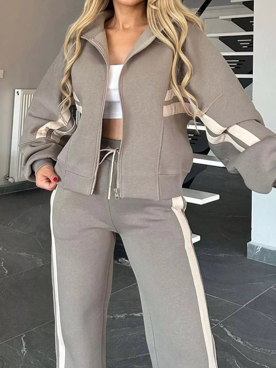 Close-up of the taupe zip up jacket with striped sleeves and drawstring pants