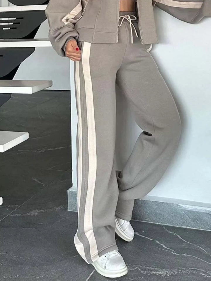 Taupe tracksuit pants with cream side stripe, lower body view with sneakers