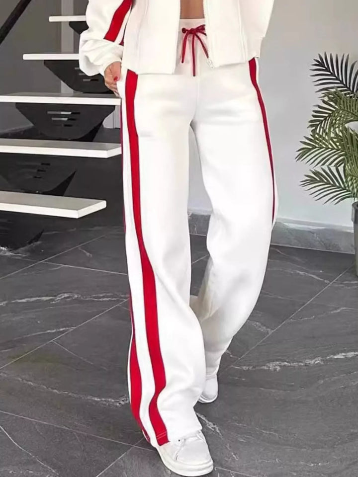 White tracksuit pants with red side stripe and white sneakers