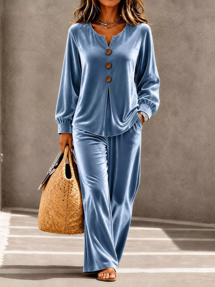 Dusty blue velvet-look top and wide leg pants set, walking with a straw tote