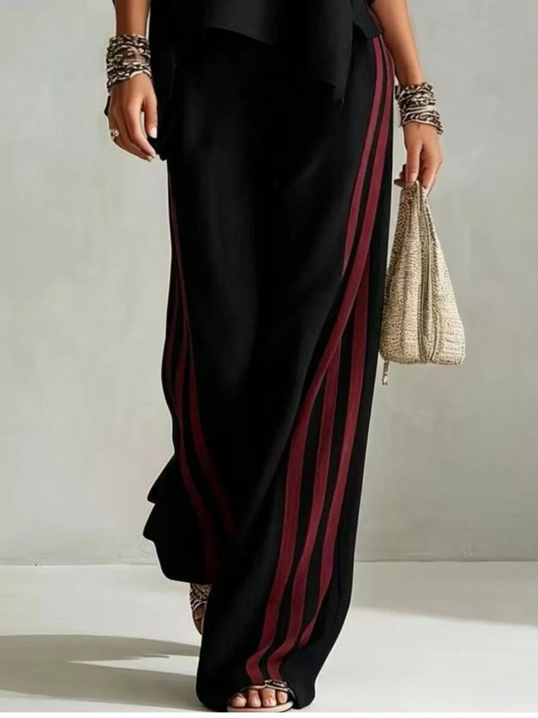Detail of the black striped wide leg pants with side stripes and a bag