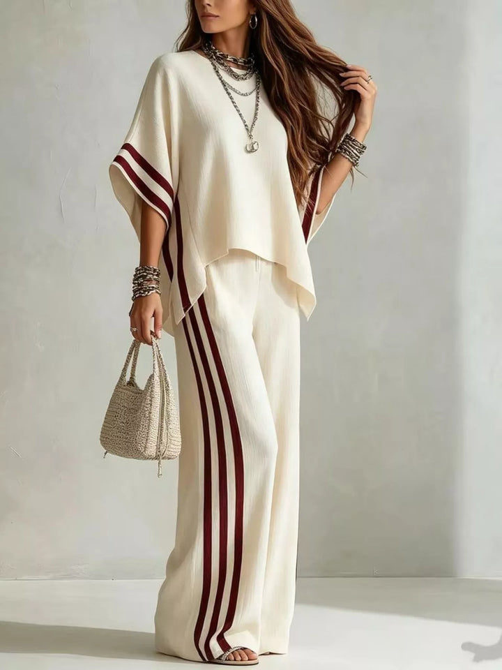 Cream striped pants set in a side angle, holding a small handbag