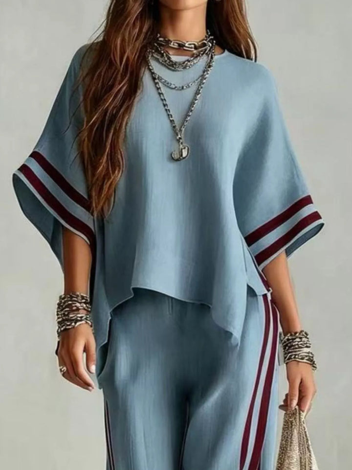 Close-up of the steel blue top with striped cuffs and layered necklaces