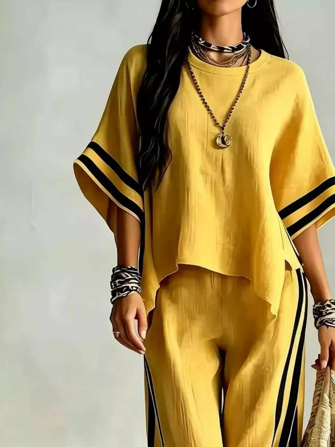 Close-up of the yellow top with striped sleeves and pants, holding a bag