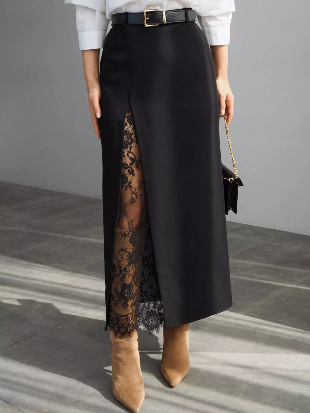 Black maxi skirt with a high waist and lace trim front slit, styled with a belt