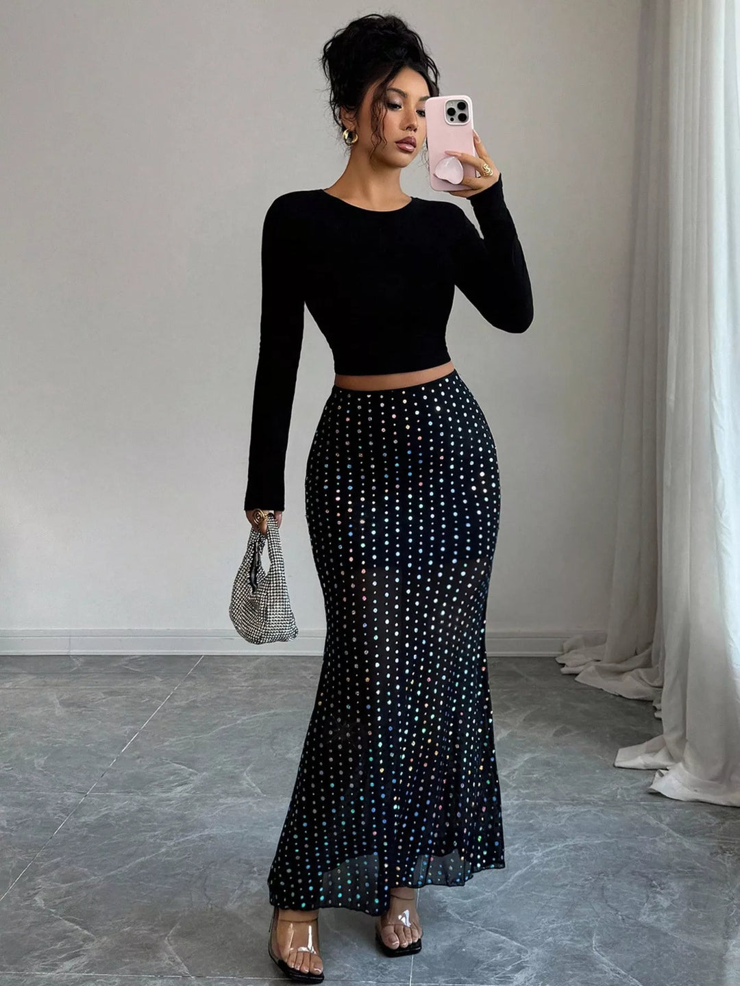 Full-length front view of the black maxi skirt styled with a black long sleeve top