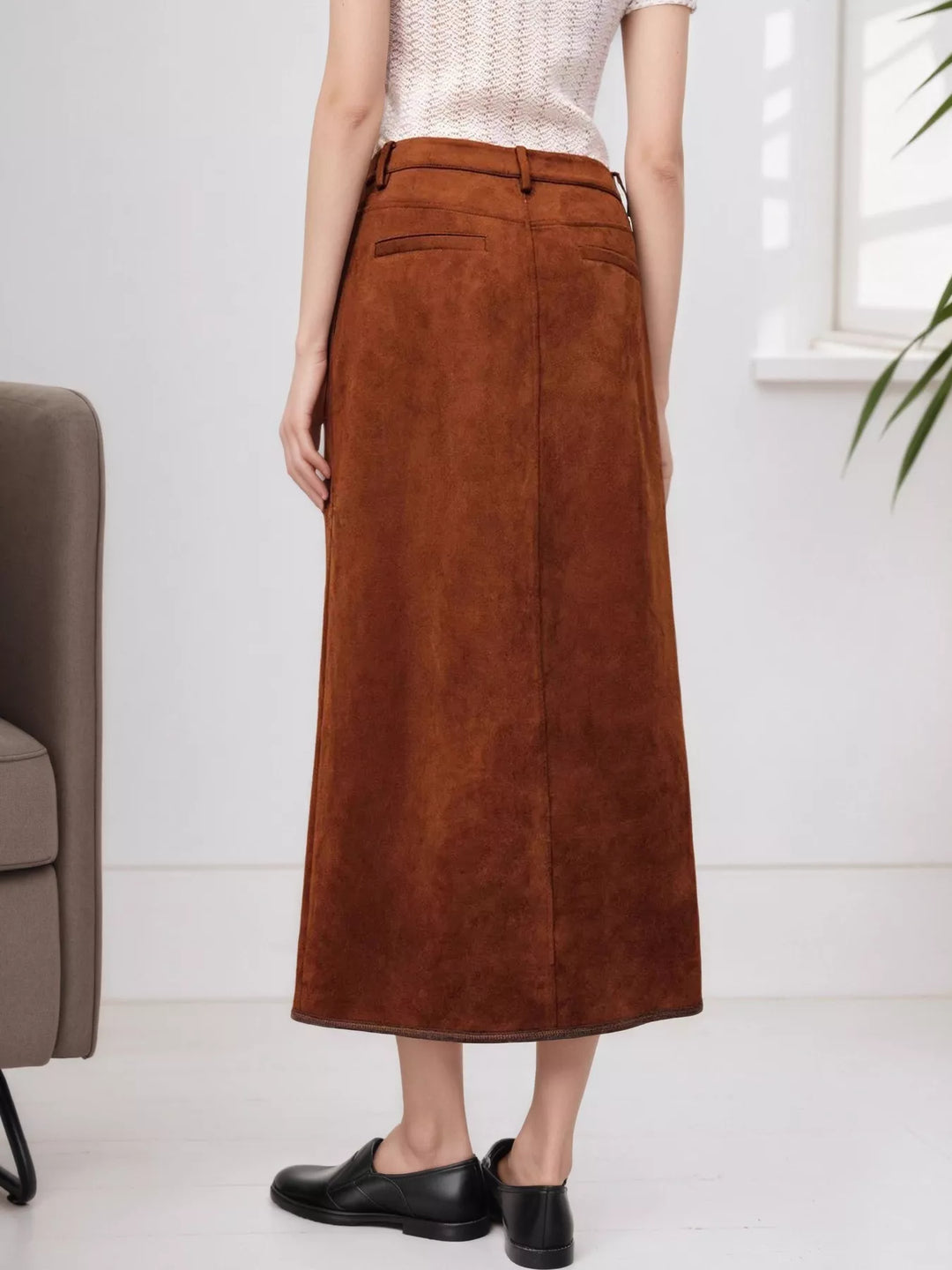Back view of the rust high waisted midi skirt, worn with black flats