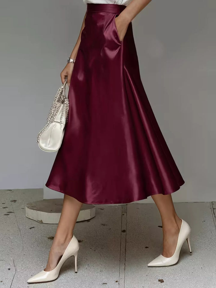 Side view of the burgundy high waisted A line midi skirt with a hand in pocket