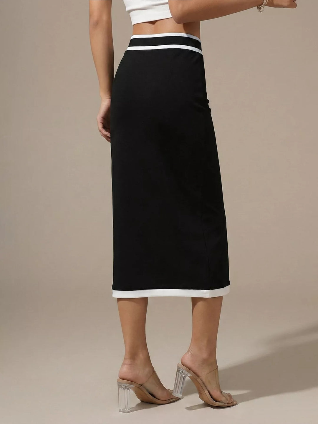 Back view of the black high waisted midi skirt showing the slit and white hem