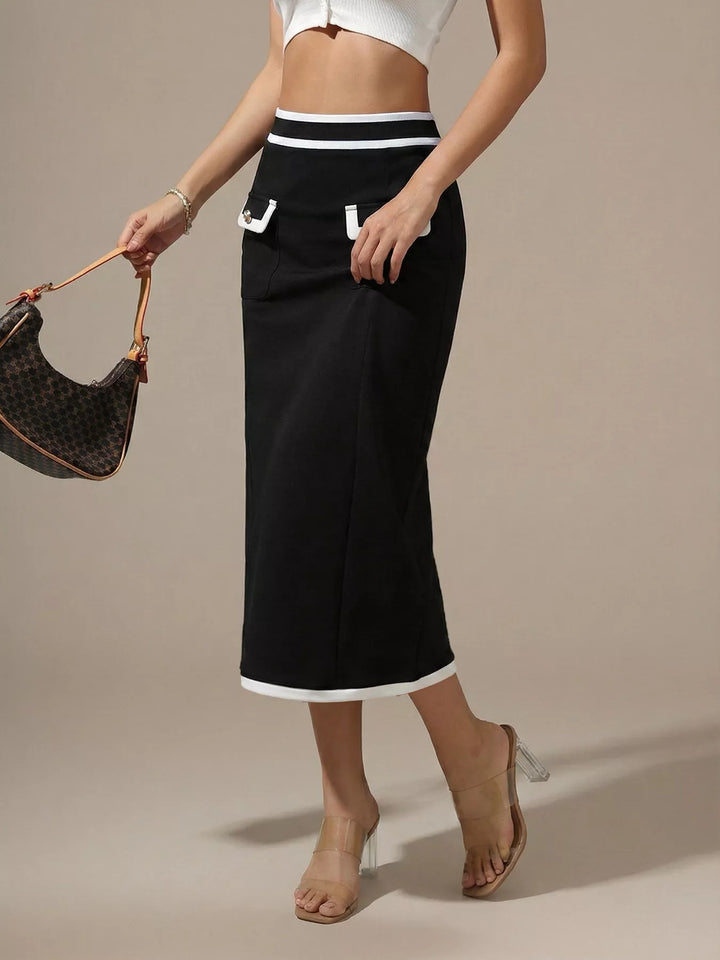 Three quarter view of the black midi skirt with contrast white hem and bag in hand