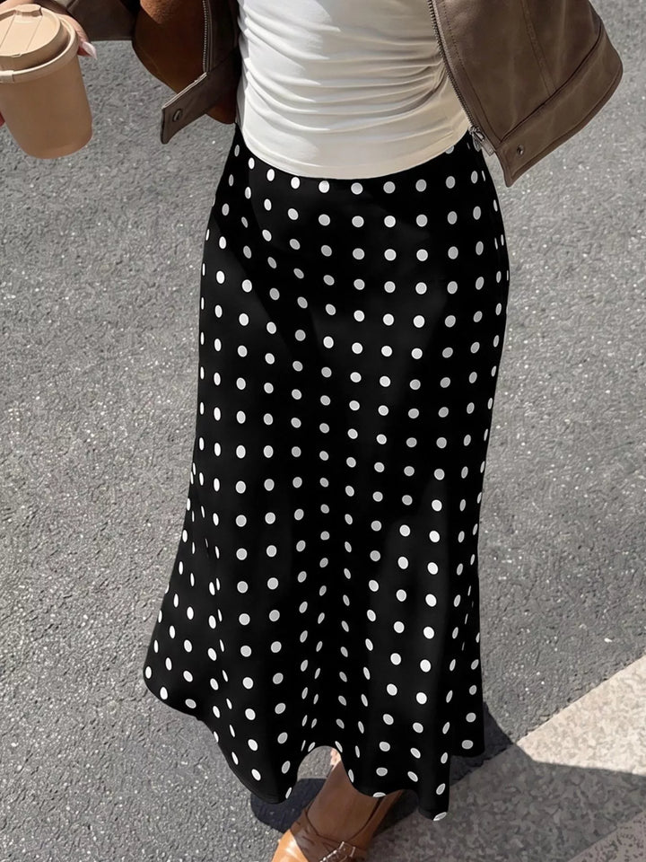 Black polka dot skirt with flared hem, cropped view with coffee cup