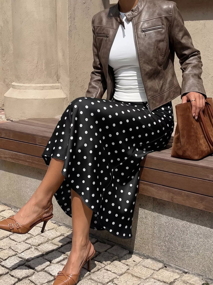 Seated in the black polka dot midi skirt with a brown leather jacket