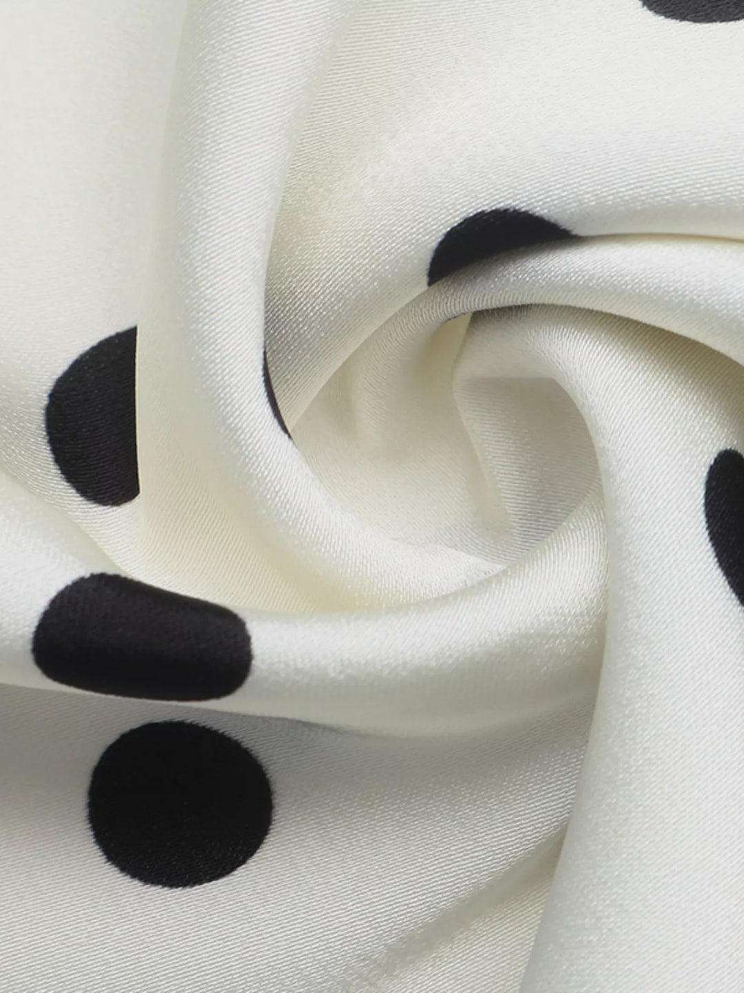 Swirled cream satin-look fabric showing the black polka dots