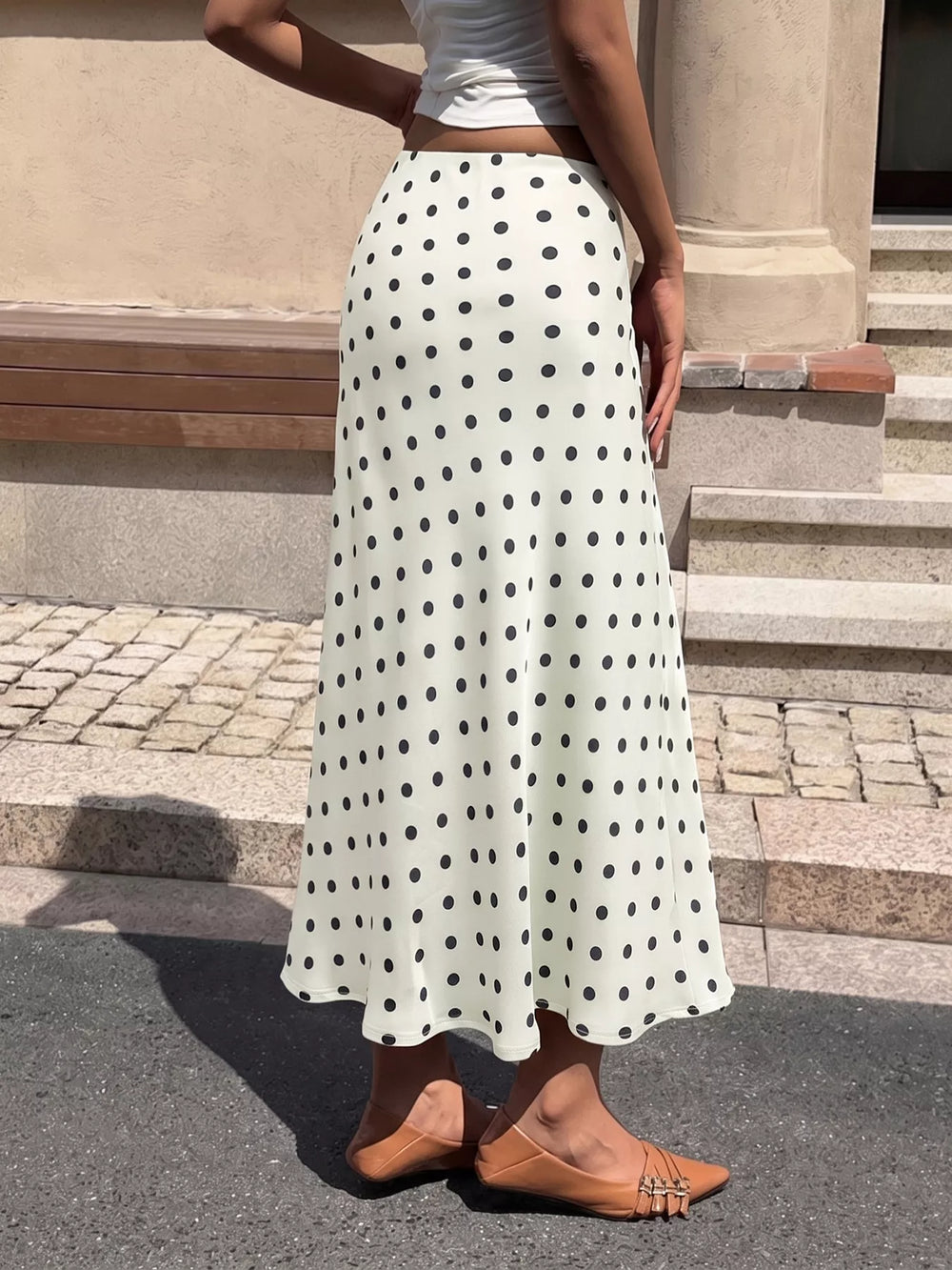 Cream polka dot satin-look midi skirt from a side angle on a city street