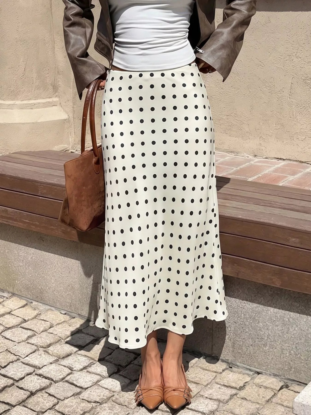 Cream flared midi skirt with a tote bag, standing on cobblestones