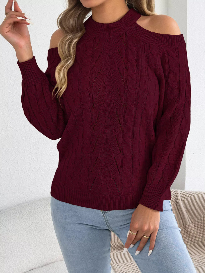 Burgundy cutout sweater styled with a hand raised to the hair