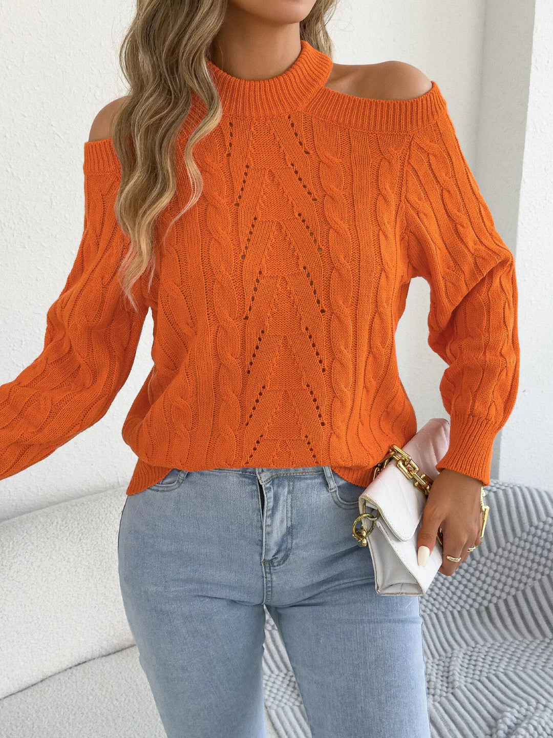 Orange cable knit sweater carried with a white handbag
