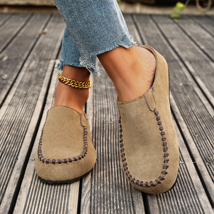 Beige slip on mules worn with raw hem jeans