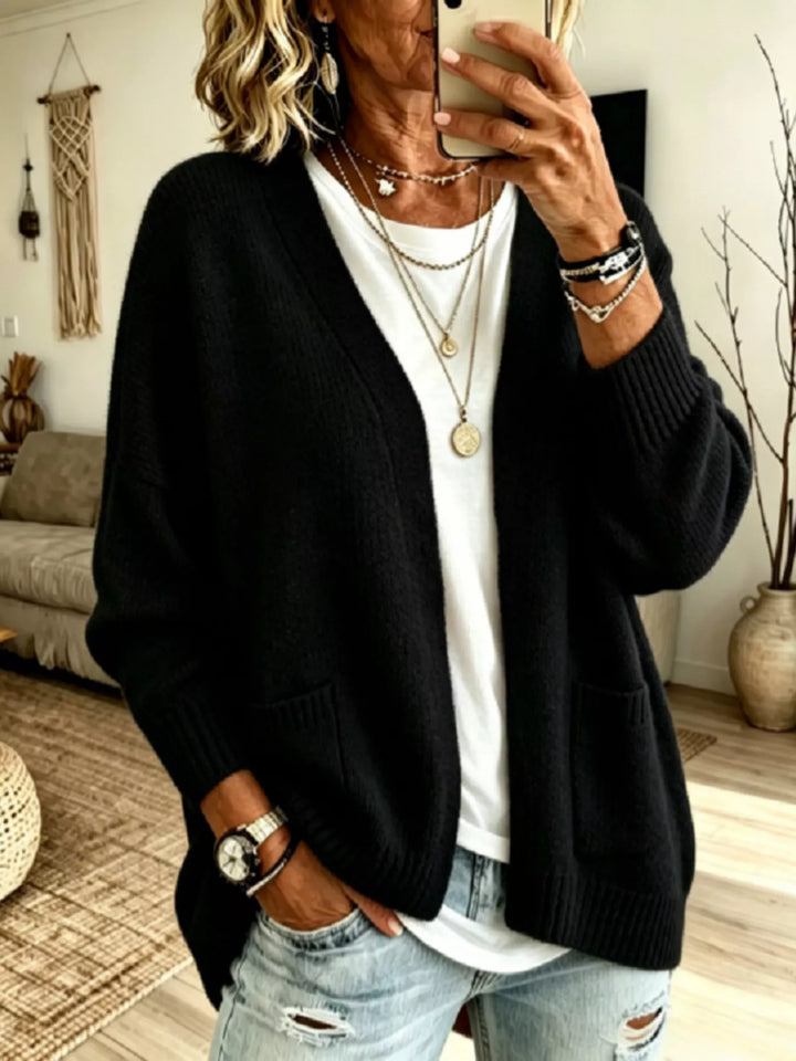 Black oversized open front cardigan with V neck and pockets, worn with ripped jeans