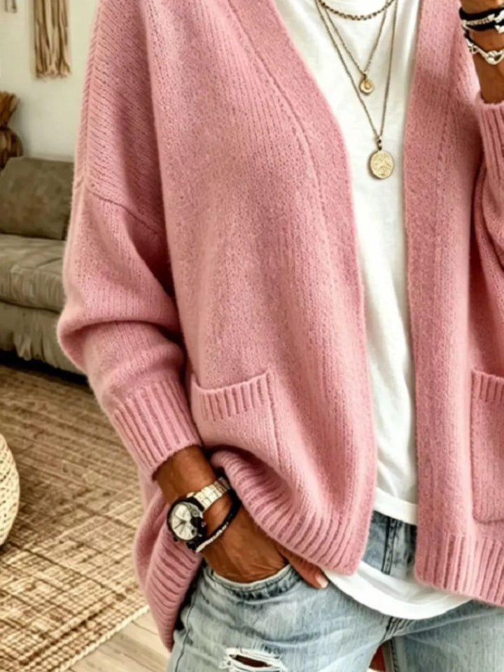 Close-up of the dusty pink cardigan pocket and ribbed hem with a hand in jeans