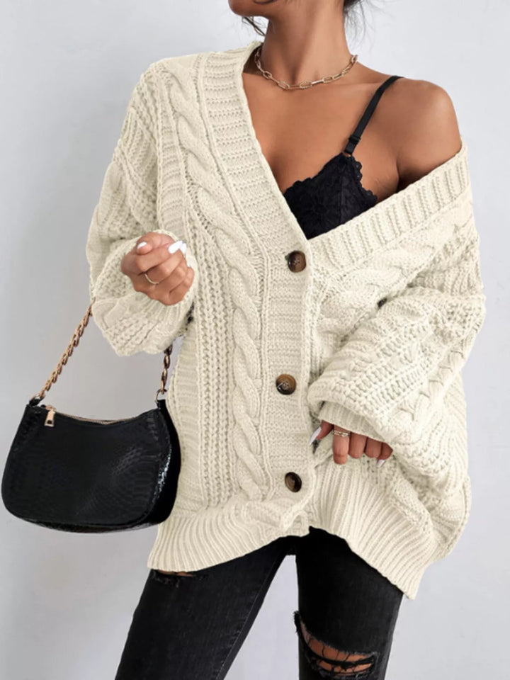 Cream cable knit cardigan off the shoulder, styled with a black shoulder bag