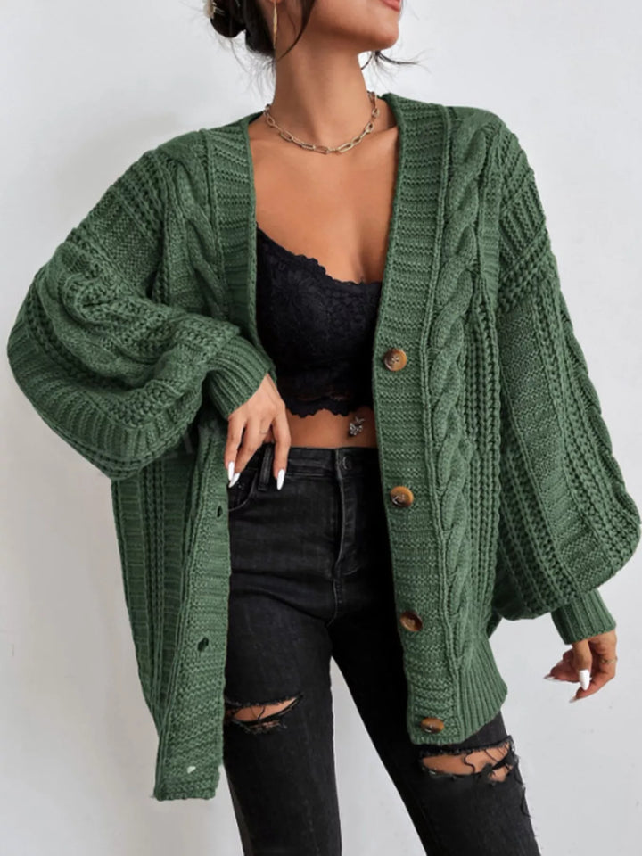 Forest green button front cardigan worn open over a black top and ripped jeans