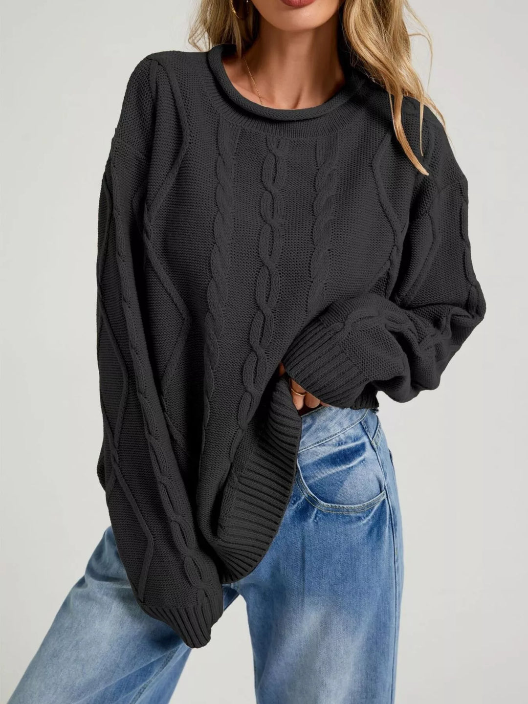 Black oversized cable knit sweater with rolled neck, styled with light jeans