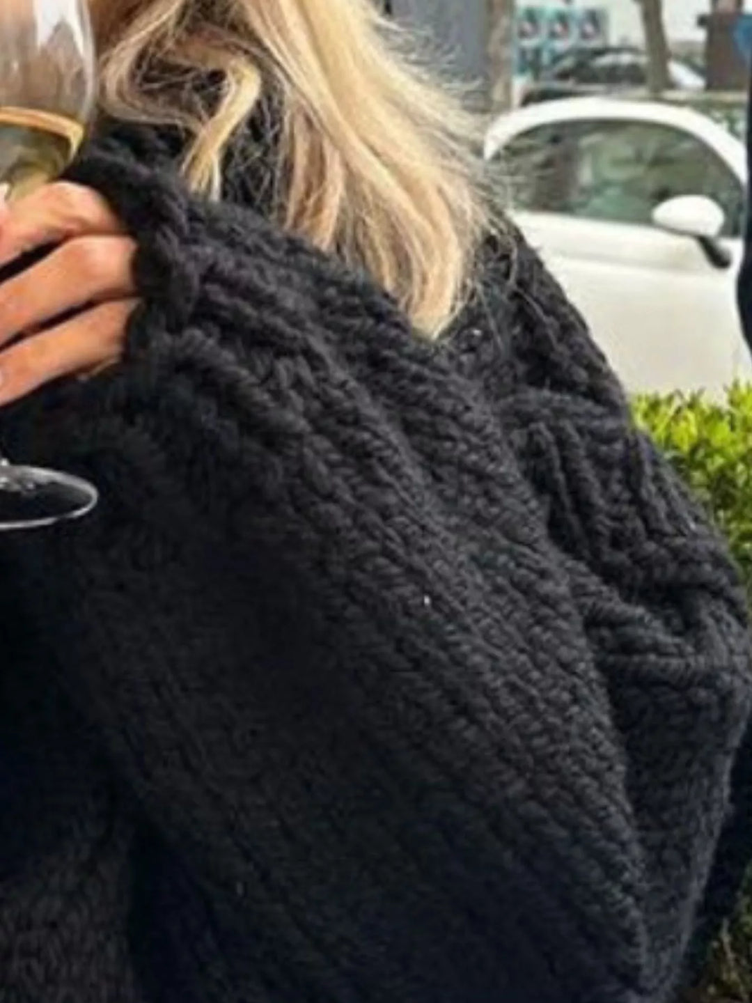 Close-up of the black chunky knit texture and layered shoulder