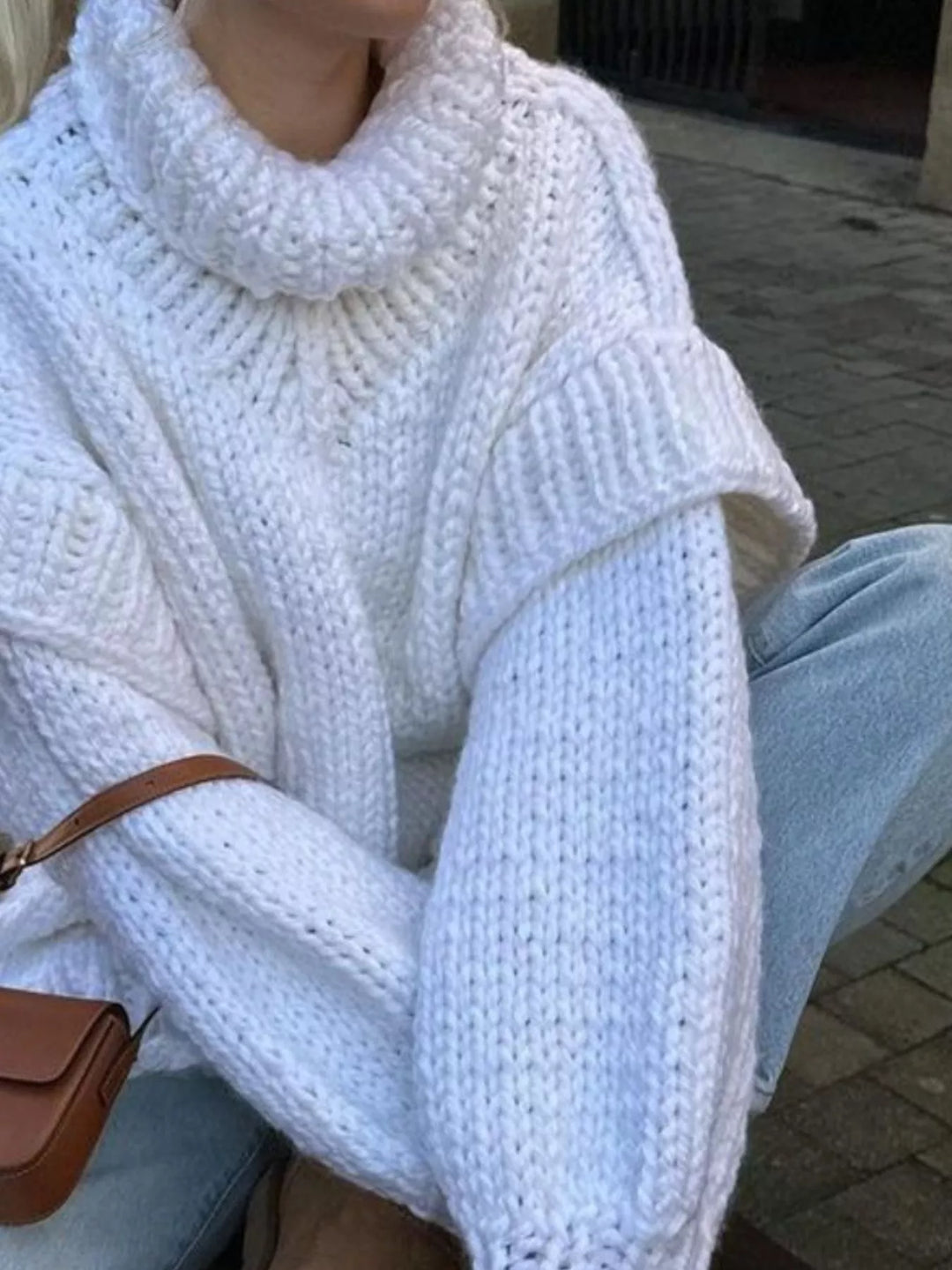 White oversized turtleneck sweater with layered shoulders and a crossbody bag