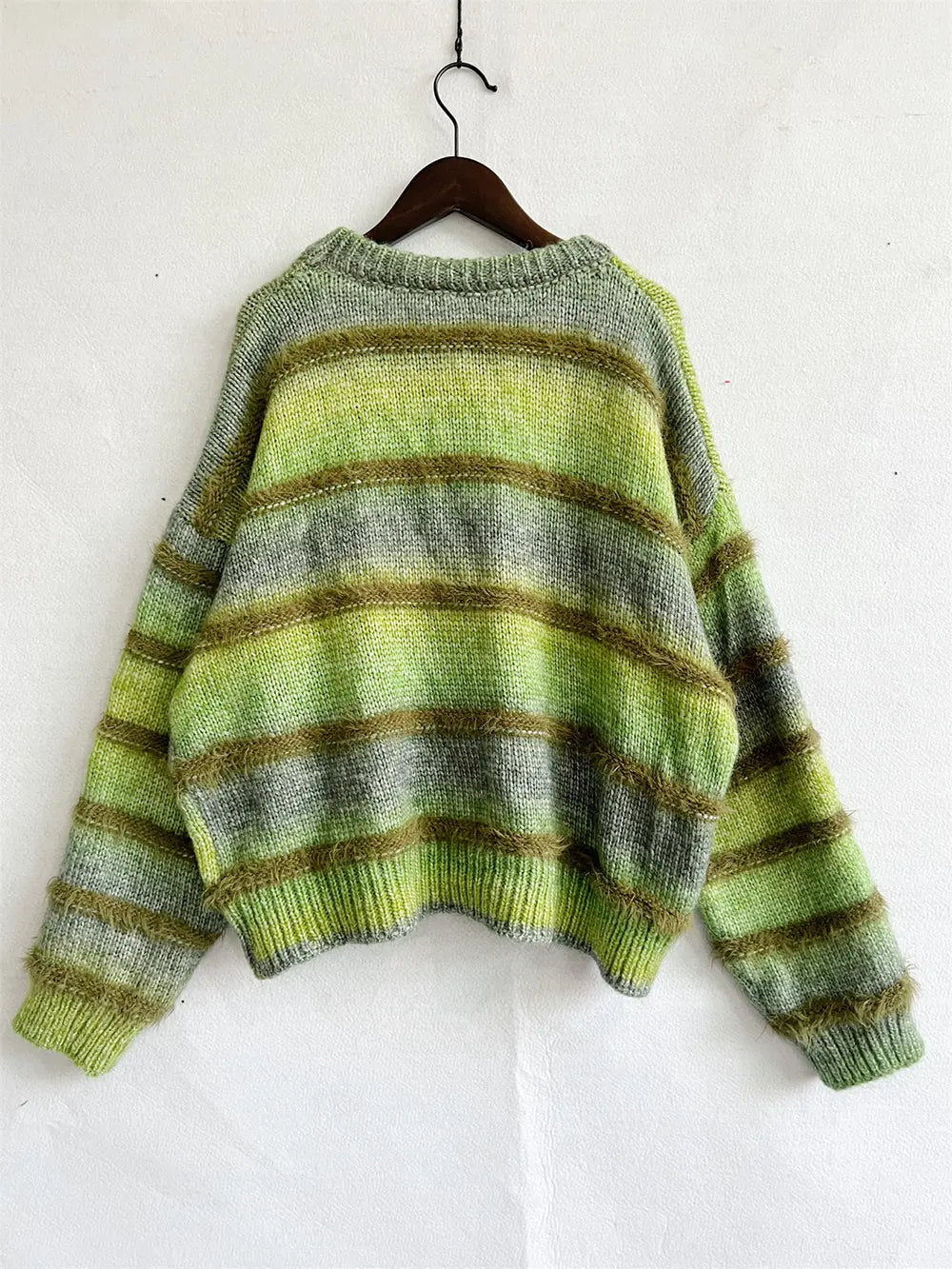 Green fuzzy knit sweater on a hanger with sleeves spread
