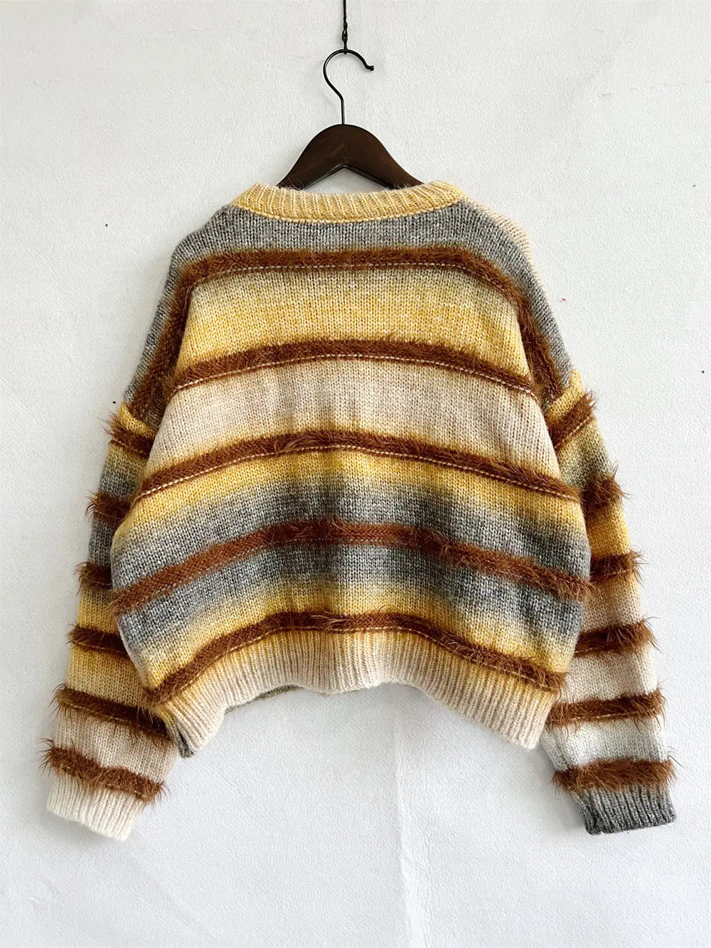 Ochre round neck sweater on a hanger with sleeves spread