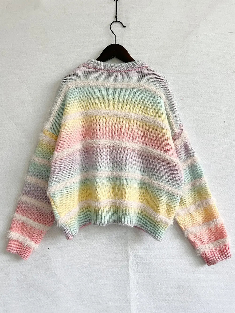 Pastel striped round neck sweater on a hanger, sleeves relaxed