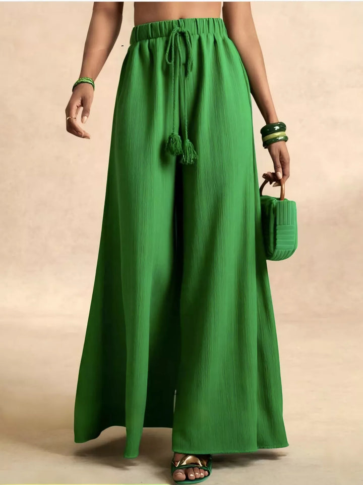 Green palazzo pants with tassel drawstring, carried with a green clutch