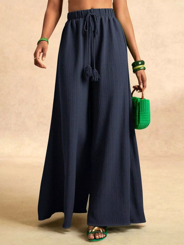 Navy flowy palazzo pants with a drawstring waist, worn with a green bag