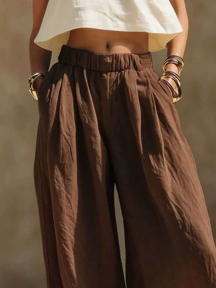 Chocolate palazzo pants waist close-up with pleats and a cream cropped top