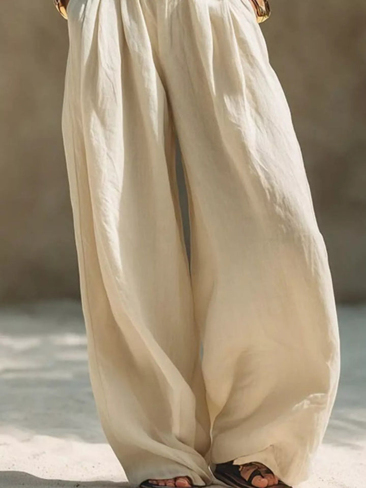 Cream palazzo pants close-up of the flowing wide legs and pleats